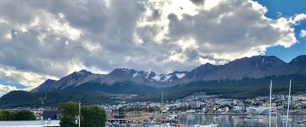 Panoramic shot of buildings by mountains against sky