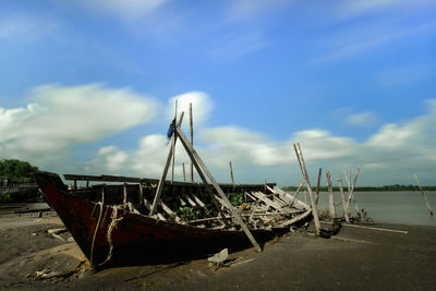 Abandoned boat moored on beach against sky