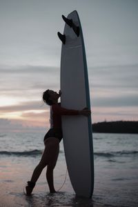 Woman standing on beach against sky during sunset