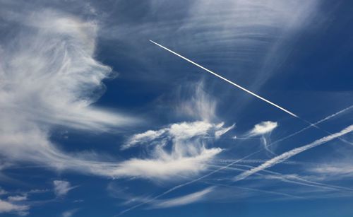 Low angle view of vapor trails against blue sky