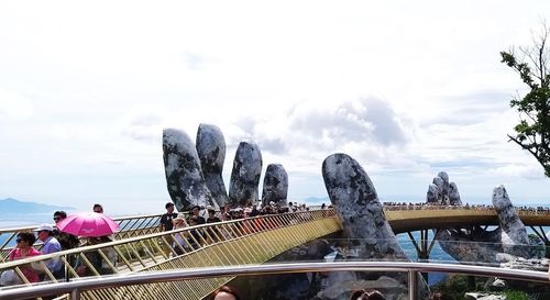 Statue of people on railing against cloudy sky