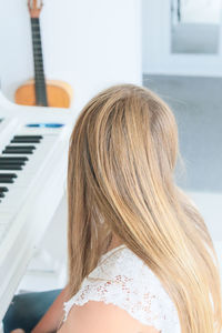 High angle view of blond woman sitting by grand piano at home