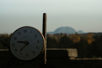 Close-up of clock on wood against sky