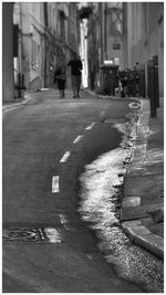 Man walking on road along buildings