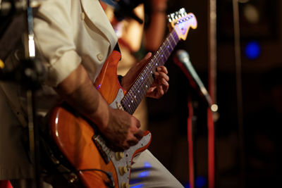 Close-up mid section of a man playing guitar