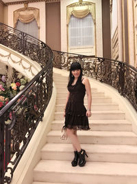 Full length portrait of woman standing on staircase