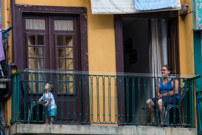 Woman sitting on window of building