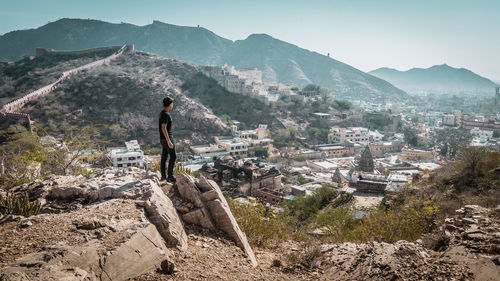 Side view of man looking at city and mountains from cliff