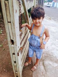 Portrait of cute boy standing by wooden gate