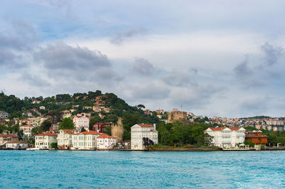 Scenic view of sea by cityscape against sky