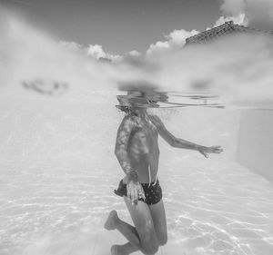 Low section of boy swimming in pool against sky