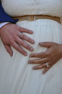 Cropped hand of man touching stomach of pregnant bride