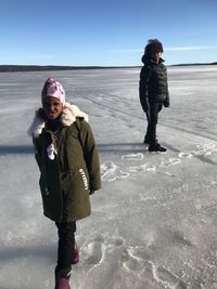 Full length of urban siblings standing on frozen lake