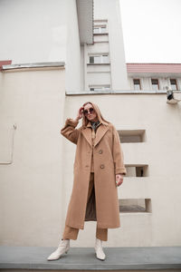 Female fashion model, posing for a full length photo, wearing total beige outfit, street fashion