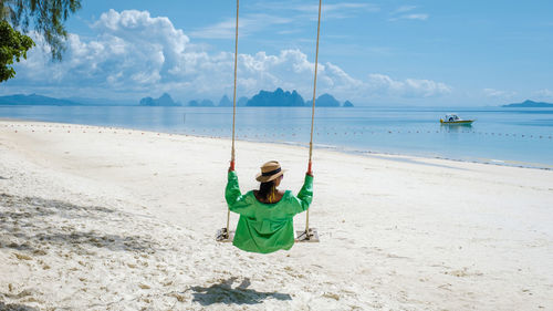 Rear view of woman swinging at beach