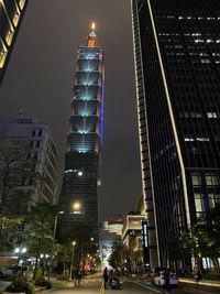 Illuminated modern buildings in city against sky at night