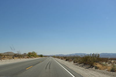 Empty road against clear blue sky