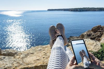 View trekking feet making photography with smart phone on cliff in front of the sea vacation concept