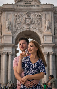 Smiling couple standing against building