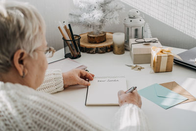 Wishlist, modern letters to santa claus from adults. senior mature old woman in white sweater