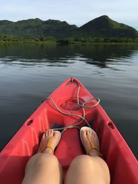 Low section of woman sitting on boat in lake against mountains