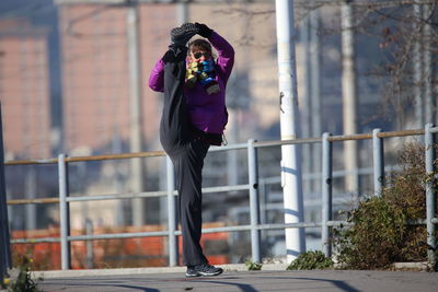 Full length portrait of woman stretching legs on road