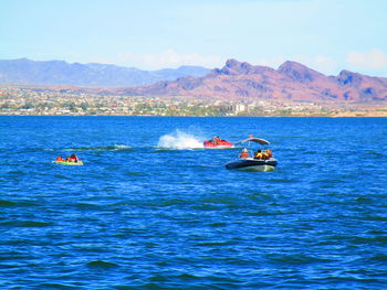 People on boat in sea against sky