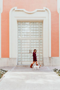 Woman walking with dog on footpath by entrance