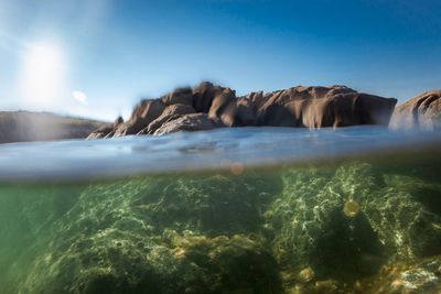 Rocks in sea against sky, simultaneous view under and over the water