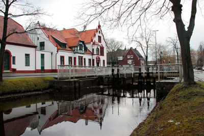 Houses by river and buildings against sky