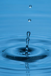 Close-up of drop falling on blue water