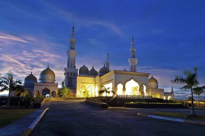 Illuminated mosque against sky at night