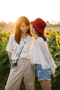 Female friends standing at sunflower farm