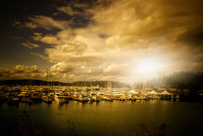 Sailboats moored at harbor against sky during sunset