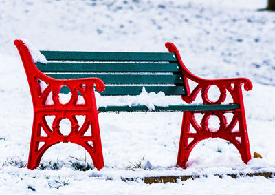 Close-up of snow on bench at park during winter