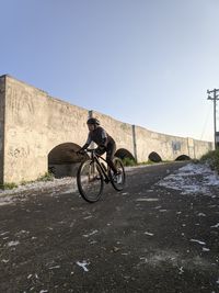 Man riding bicycle on road against clear sky