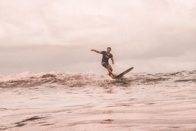 Man surfing in sea against sky