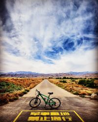 Bicycle parked on road against sky