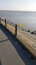 Rear view of people walking by sea against sky