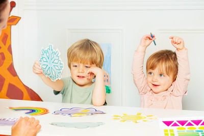 Portrait of siblings playing with toys while sitting on sofa at home