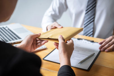 Midsection of businesswoman bribing businessman in office