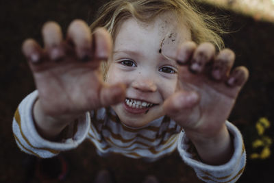 High angle portrait of happy girl gesturing while standing on field