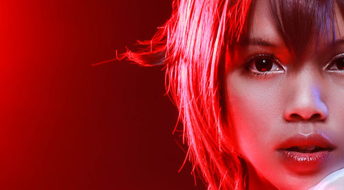 Close-up portrait of beautiful woman against red background