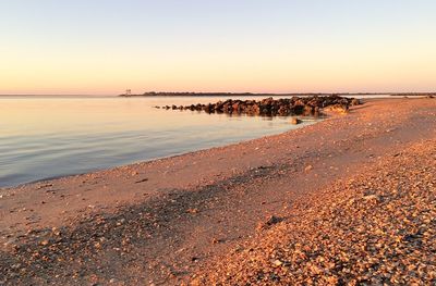 Scenic view of beach against sky at sunset