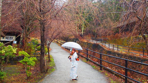 Rear view of woman walking on umbrella during rainy season