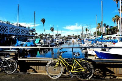 Bicycles parked at harbor against blue sky