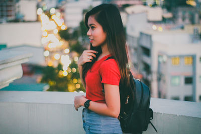 Young woman standing against wall in city