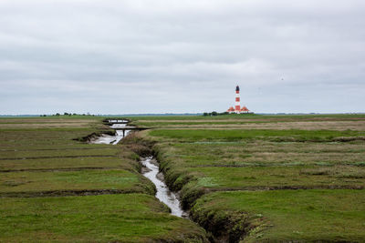 Lighthouse on field against sky