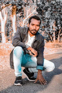 Portrait of young man sitting on road