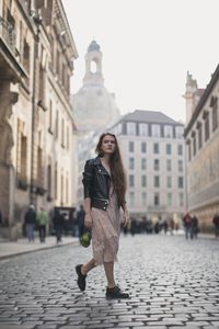 Full length of woman walking on street against buildings in city
